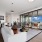 Spacious and well lit living room with wood flooring, large windows and open access to the kitchen